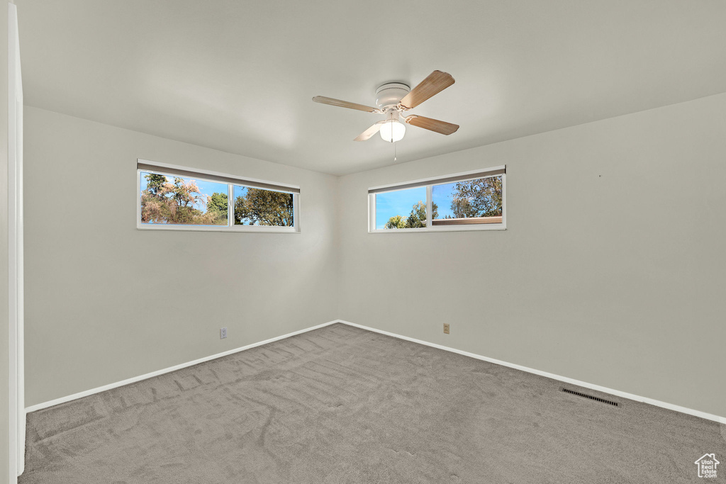 Carpeted empty room with a ceiling fan and baseboards