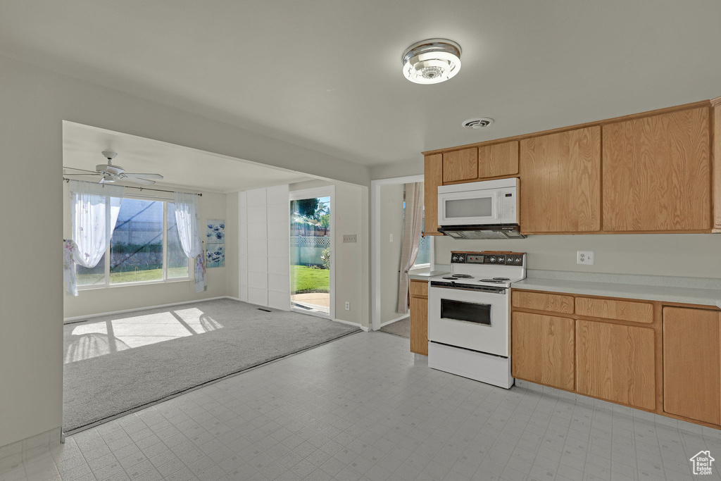 Kitchen featuring white appliances, light flooring, light countertops, a ceiling fan, and open floor plan