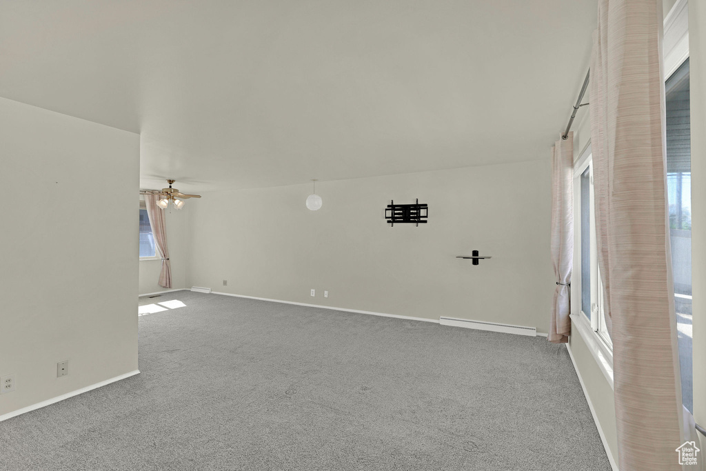 Carpeted spare room with baseboards, baseboard heating, and ceiling fan