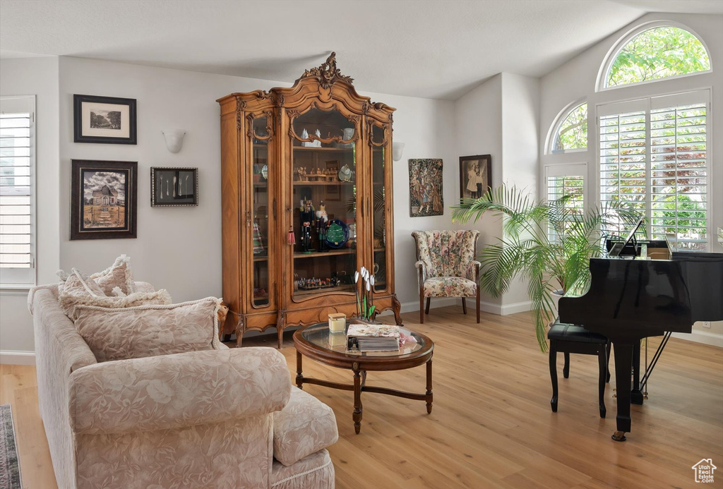 Living area featuring light wood finished floors, vaulted ceiling, and baseboards