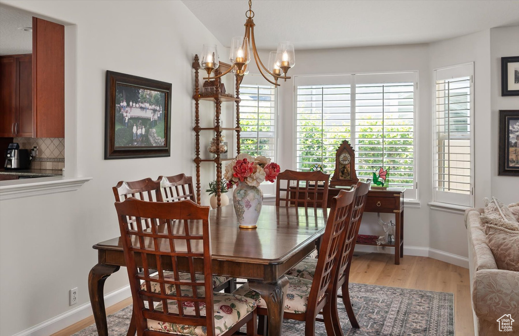 Dining room with light wood-type flooring, a chandelier, and baseboards