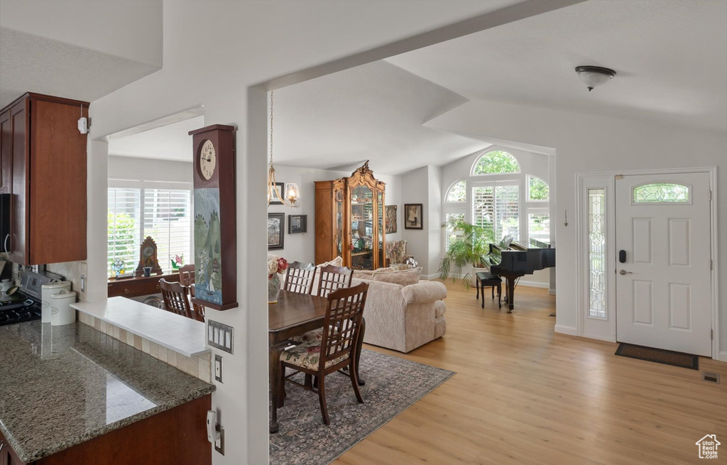 Dining space featuring light wood-type flooring, lofted ceiling, healthy amount of natural light, and a chandelier