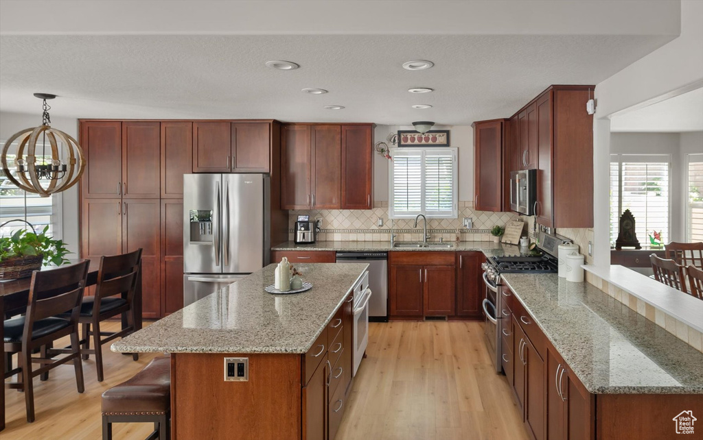Kitchen featuring appliances with stainless steel finishes, a chandelier, a sink, light wood-style flooring, and recessed lighting