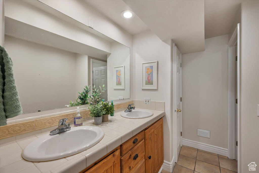 Full bath featuring double vanity, baseboards, tile patterned floors, and recessed lighting