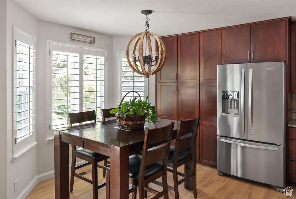 Dining space featuring a chandelier, plenty of natural light, light wood-style flooring, and baseboards