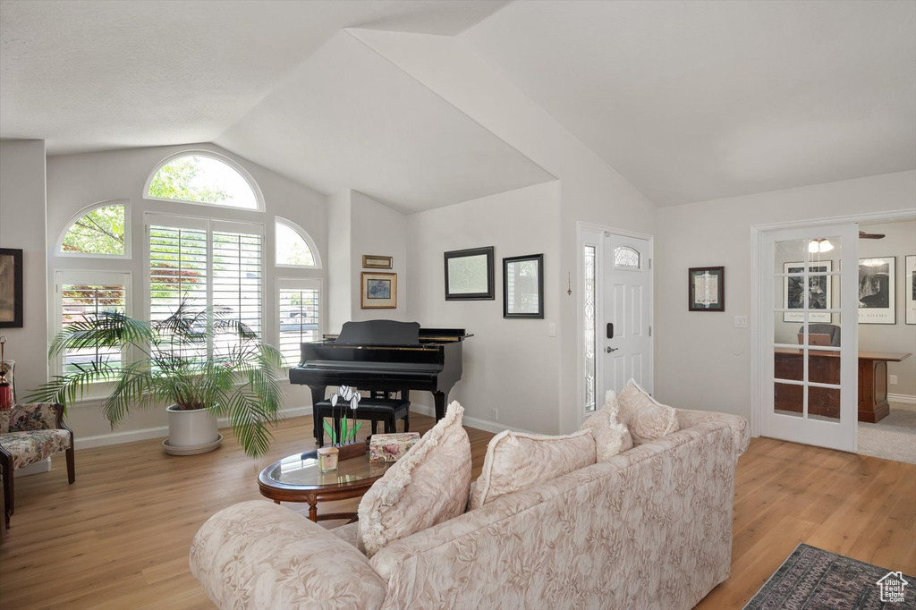 Living room featuring vaulted ceiling, light wood-style flooring, and baseboards