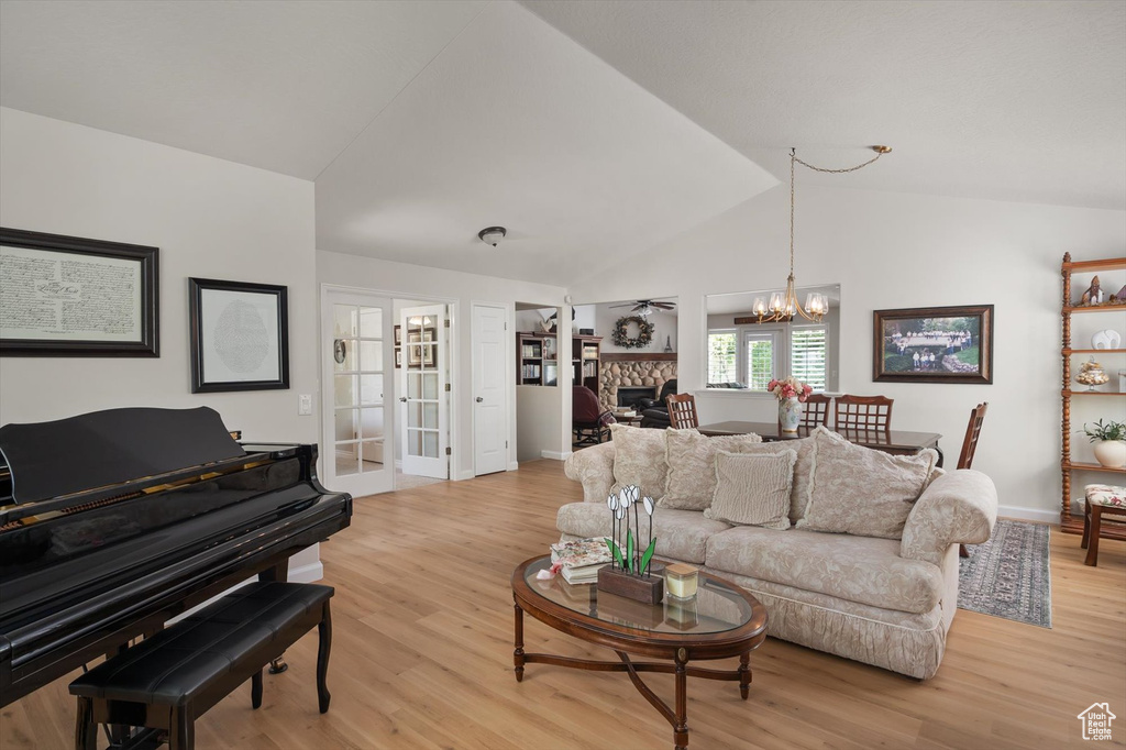 Living room with a chandelier, light wood-style floors, a fireplace, baseboards, and french doors