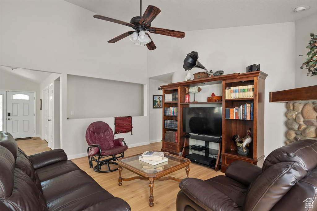 Living area featuring vaulted ceiling, a ceiling fan, wood finished floors, and baseboards