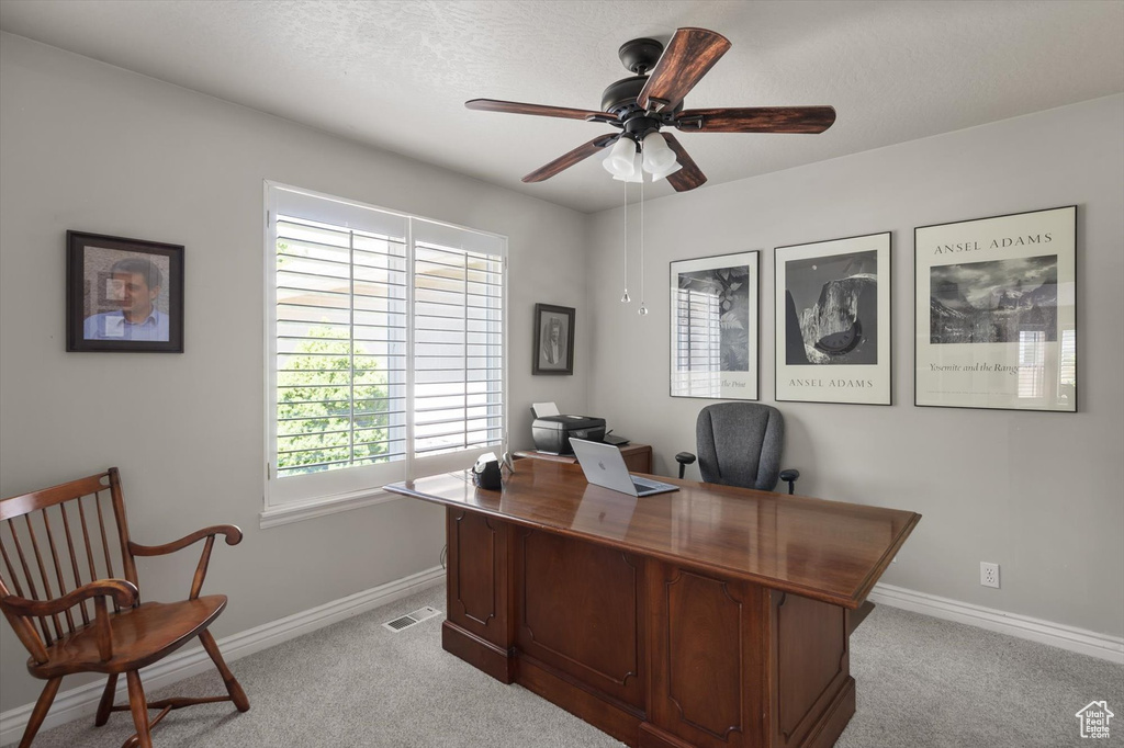 Home office featuring light carpet, ceiling fan, and baseboards