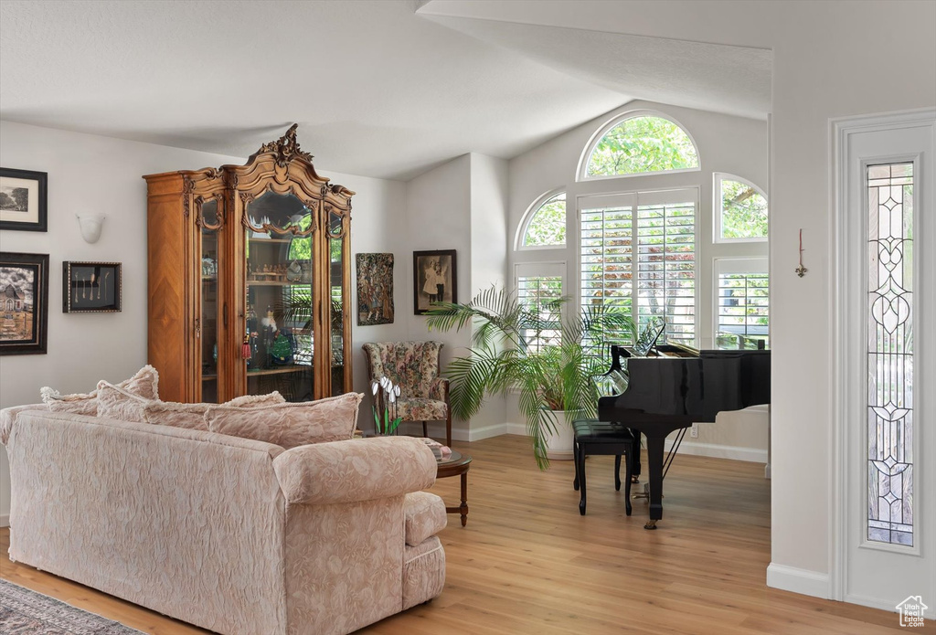 Living area with light wood-style flooring, lofted ceiling, and baseboards