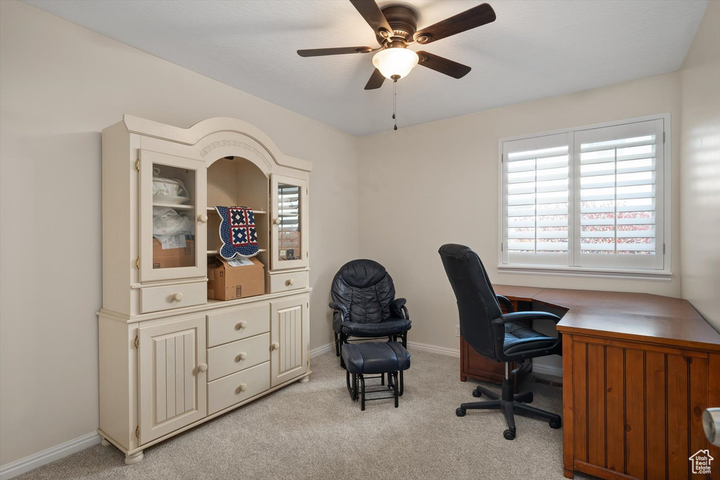 Home office with a ceiling fan, light colored carpet, and baseboards