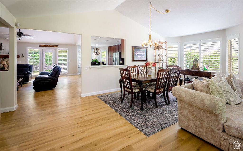 Dining space featuring a chandelier, light wood-style flooring, lofted ceiling, baseboards, and ceiling fan