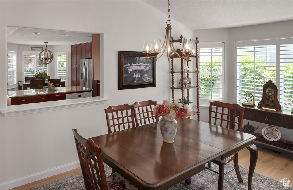Dining area featuring a chandelier, wood finished floors, lofted ceiling, and baseboards