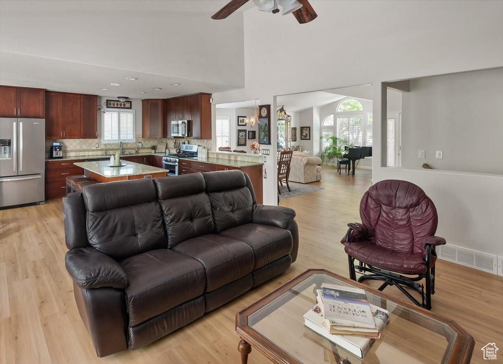 Living room featuring ceiling fan, light wood-style flooring, and a high ceiling