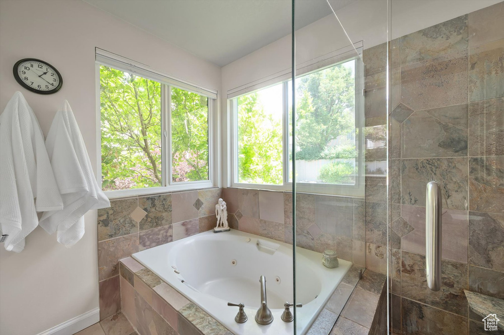 Full bath with a jetted tub, a tile shower, and baseboards