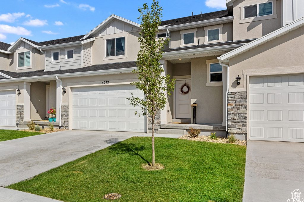 Townhome / multi-family property featuring stone siding, stucco siding, concrete driveway, and a garage