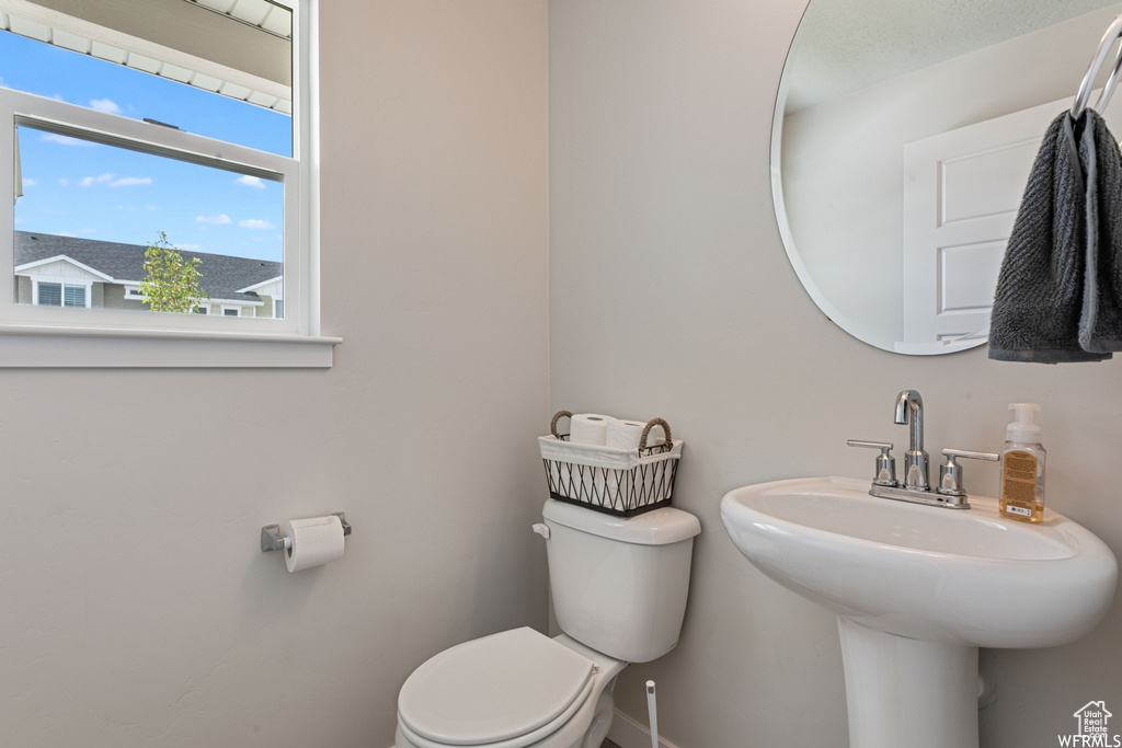 Half bath with toilet, baseboards, and a sink