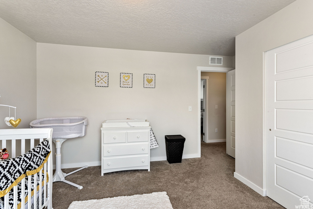 Bedroom with carpet flooring, baseboards, and a textured ceiling