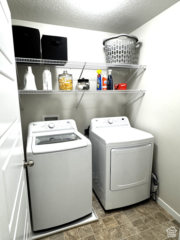 Washroom with washer and clothes dryer, baseboards, and a textured ceiling