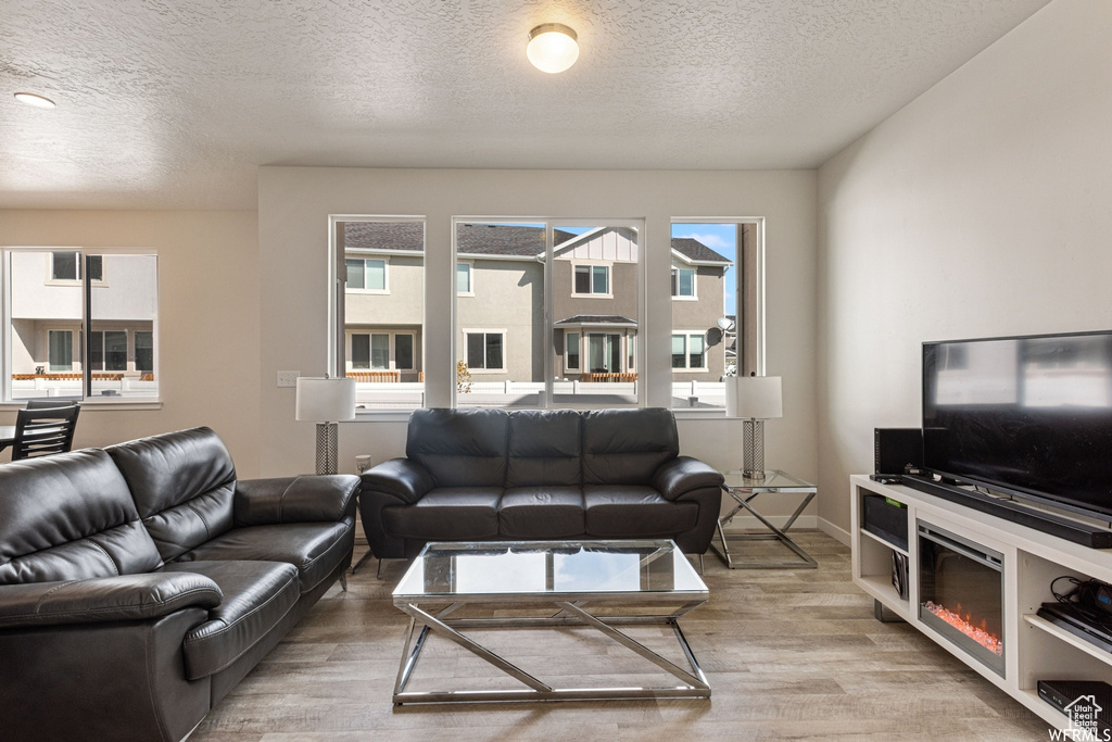Living area featuring light wood-style floors and a textured ceiling