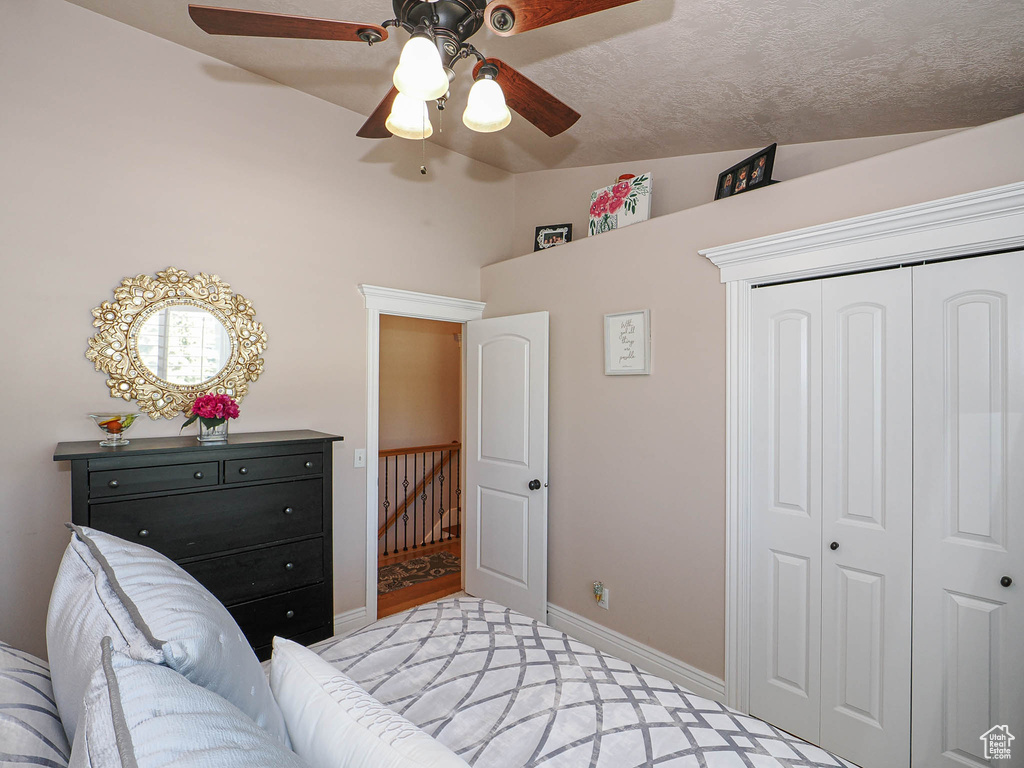 Bedroom with a closet, vaulted ceiling, a ceiling fan, and baseboards