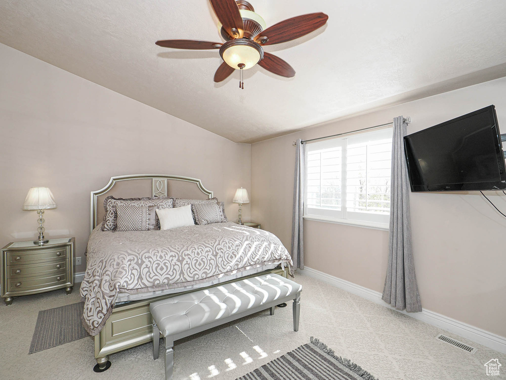 Carpeted bedroom with vaulted ceiling, baseboards, and a ceiling fan