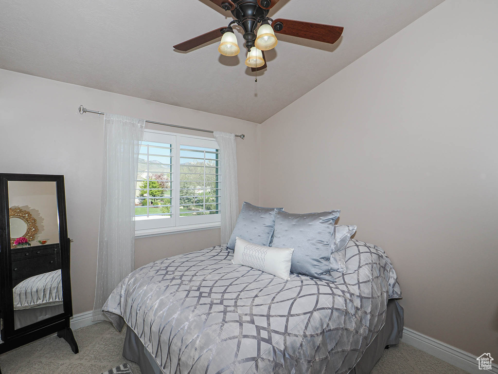 Carpeted bedroom featuring lofted ceiling, baseboards, and ceiling fan