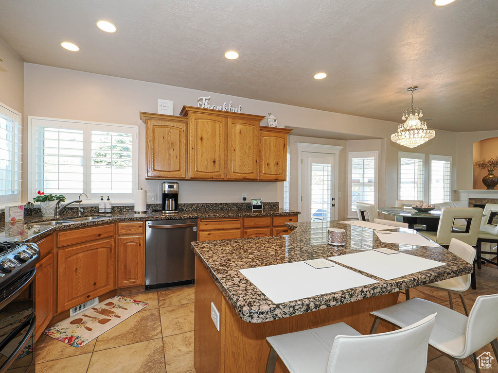 Kitchen with dishwasher, range with two ovens, a kitchen breakfast bar, a sink, and a chandelier