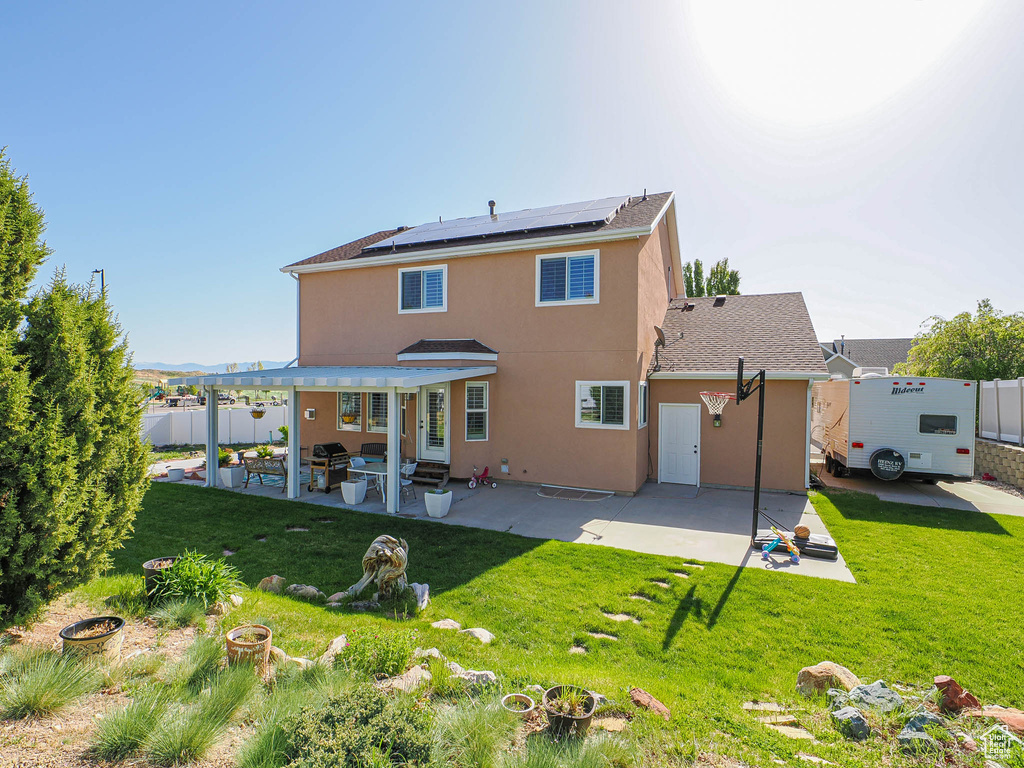 Rear view of house with roof mounted solar panels, a patio area, stucco siding, and entry steps