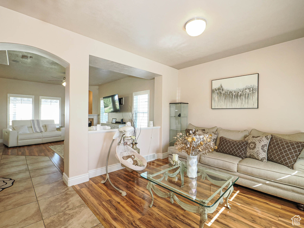 Living area with ceiling fan, healthy amount of natural light, baseboards, and wood finished floors