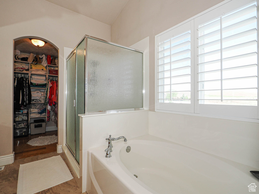 Full bathroom with a shower stall, a spacious closet, and a bath