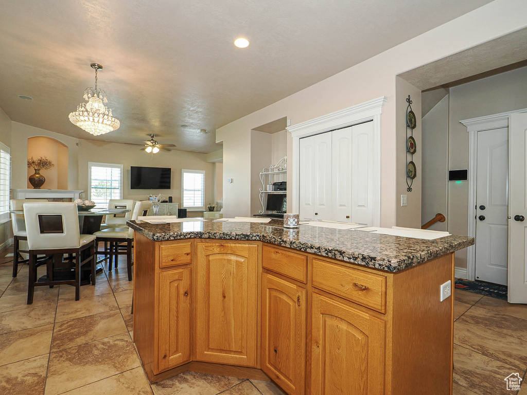 Kitchen with ceiling fan, pendant lighting, open floor plan, a center island, and a chandelier