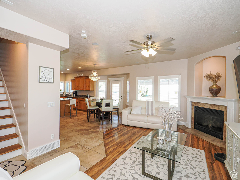 Living area featuring stairway, a ceiling fan, baseboards, a fireplace, and a textured ceiling