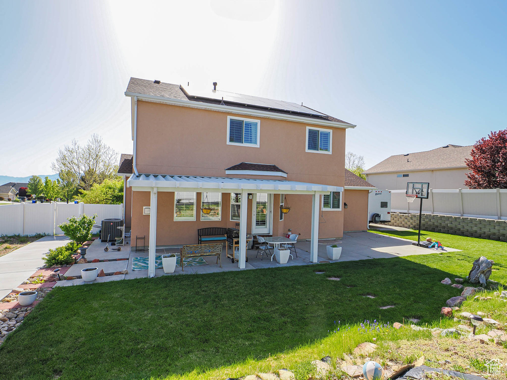 Rear view of property with solar panels, stucco siding, central AC, and a patio area