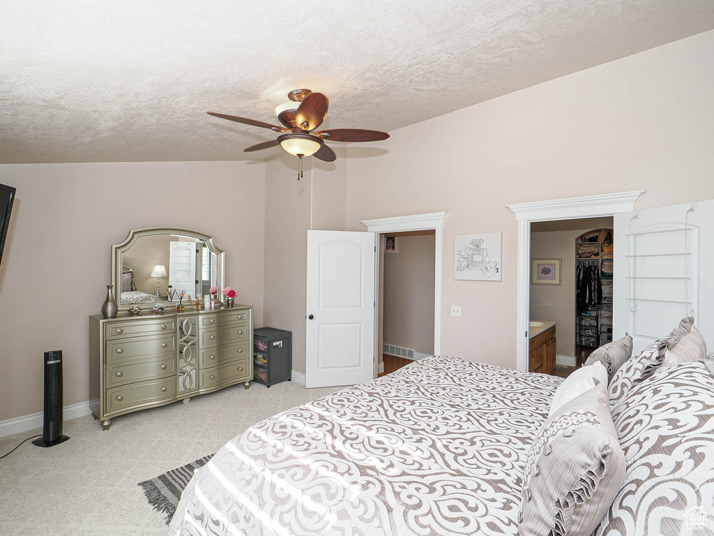 Bedroom with lofted ceiling, a textured ceiling, light carpet, a ceiling fan, and baseboards