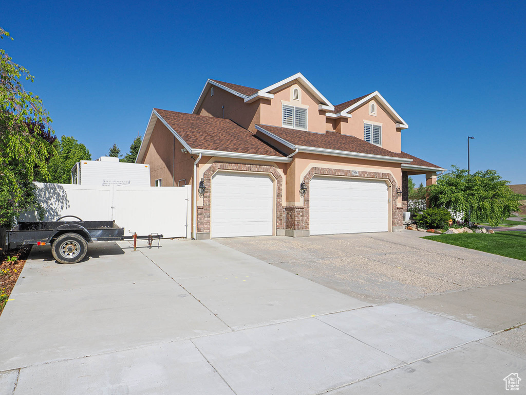 View of front of property with concrete driveway, fence, an attached garage, stucco siding, and a shingled roof
