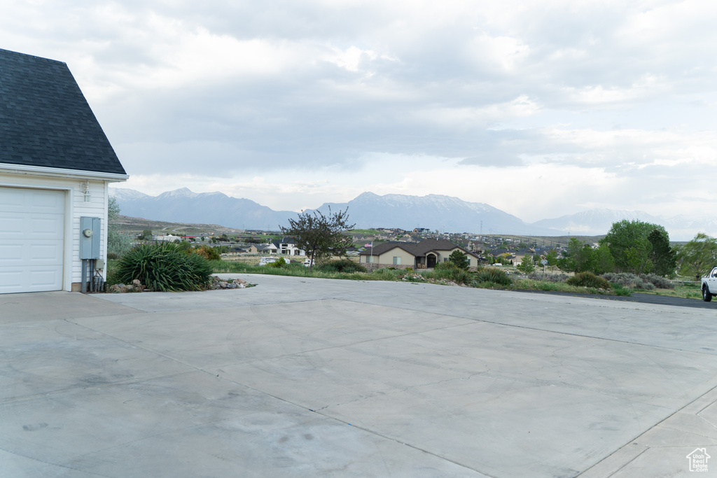 View of patio featuring a mountain view, concrete driveway, and a garage