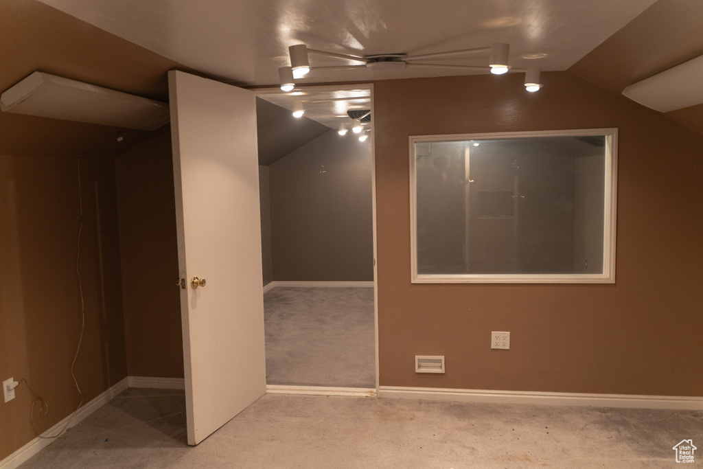 Carpeted spare room featuring vaulted ceiling and baseboards