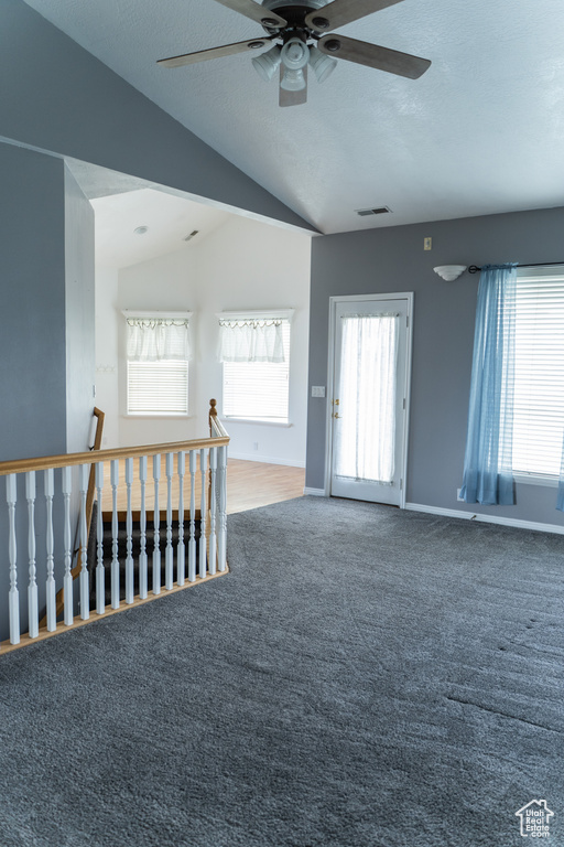 Empty room featuring ceiling fan, vaulted ceiling, carpet flooring, baseboards, and a textured ceiling