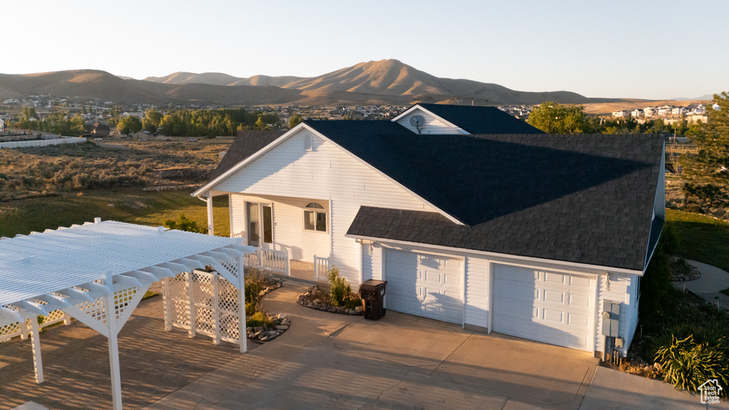 Back of property featuring a mountain view, concrete driveway, a porch, and roof with shingles