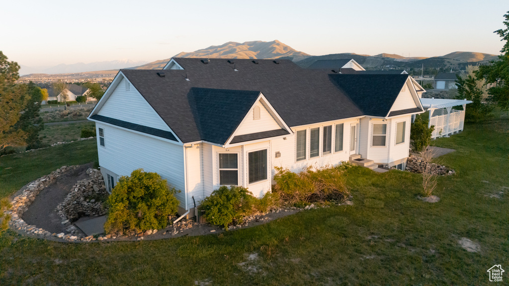 Back of property with a mountain view, a yard, a shingled roof, and entry steps