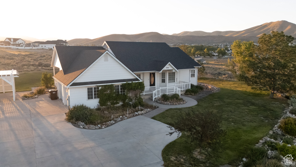 View of front of property featuring a mountain view, driveway, a front lawn, a porch, and an attached garage