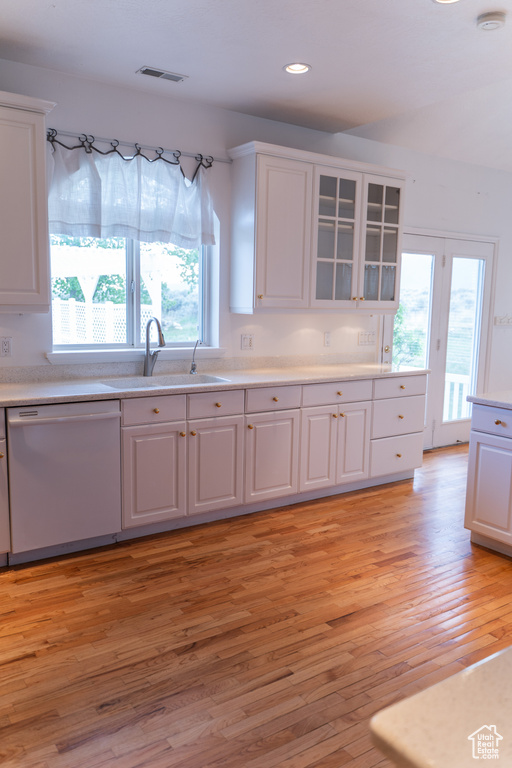 Kitchen featuring dishwasher, a sink, white cabinets, light wood finished floors, and recessed lighting