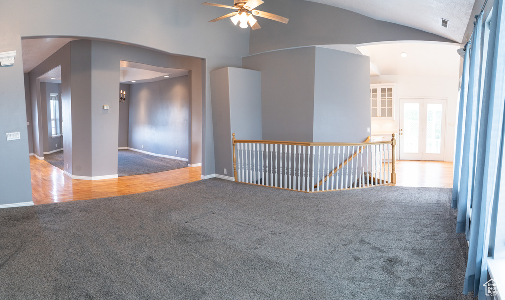 Spare room featuring carpet, arched walkways, ceiling fan, vaulted ceiling, and baseboards