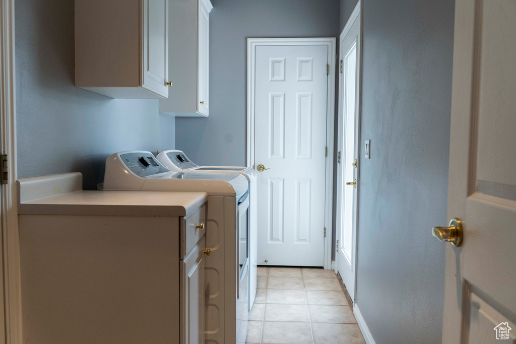 Laundry area with cabinet space, separate washer and dryer, and light tile patterned floors