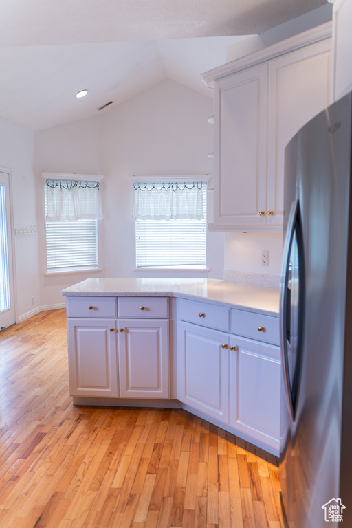 Kitchen with freestanding refrigerator, light countertops, white cabinetry, vaulted ceiling, and recessed lighting