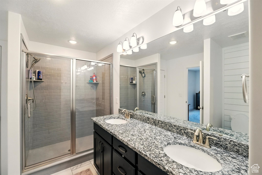 Full bath with a stall shower, double vanity, and recessed lighting