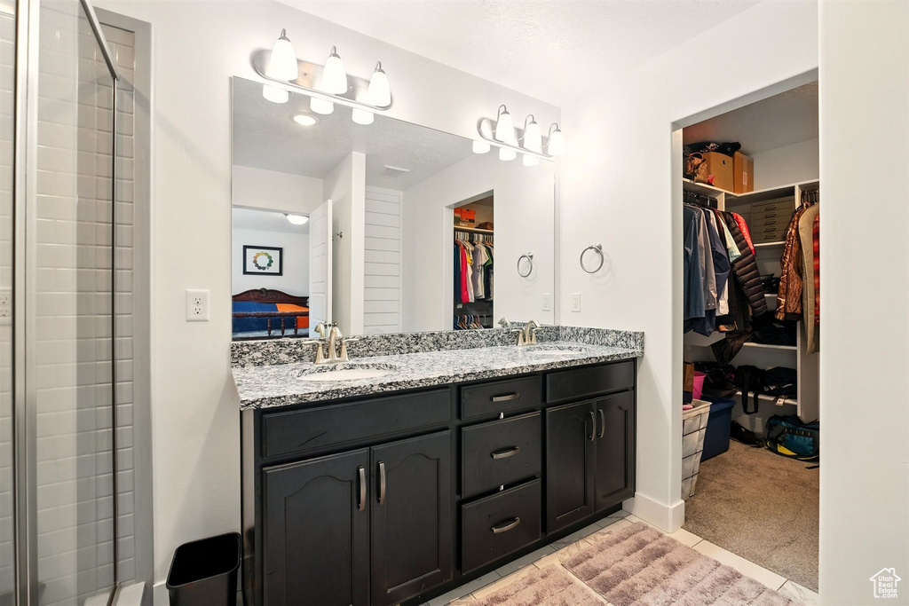 Bathroom featuring double vanity, a walk in closet, and a tile shower