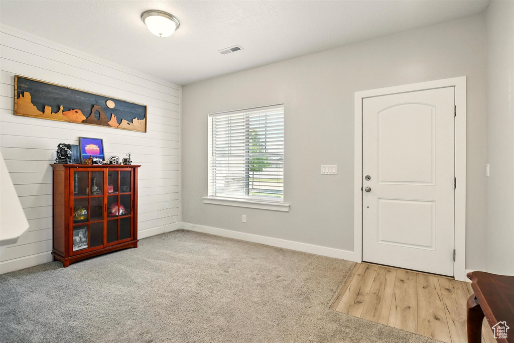 Carpeted foyer with baseboards and wood walls