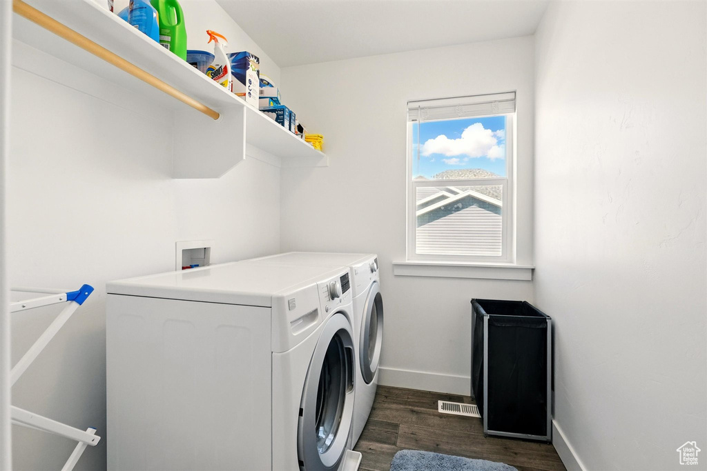 Laundry room with washing machine and clothes dryer, dark wood-type flooring, and baseboards